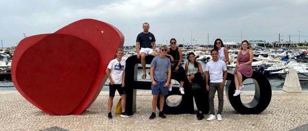 Former I-House residents gather for a reunion in Portugal, posing with a large modern art sculpture of a red heart