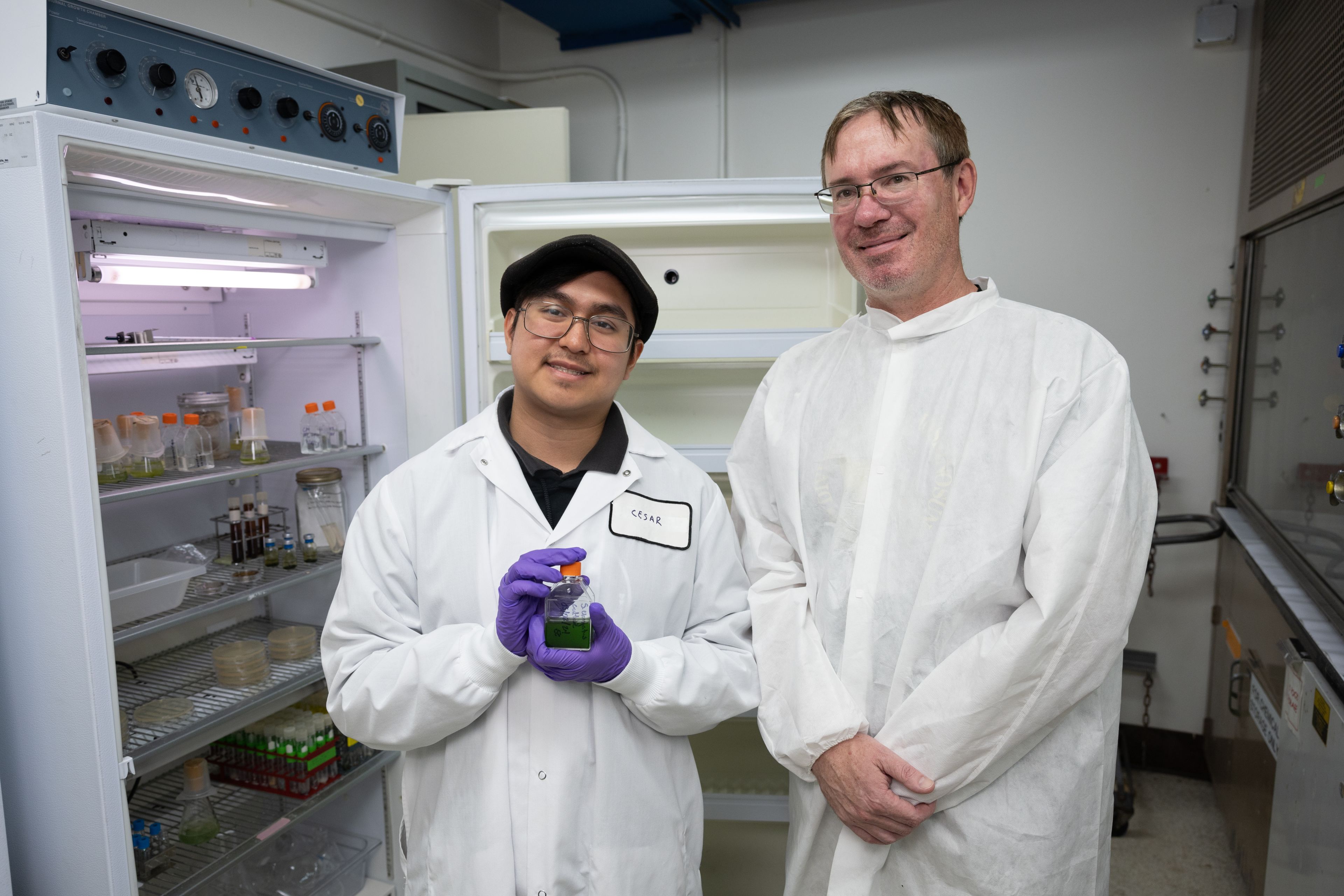 ASPIRE intern Cesar Meza with mentor Craig Everroad in the NASA Ames lab wearing labcoats in front of the lab refrigerator at NASA, NASA, astrobiology, exobiology 