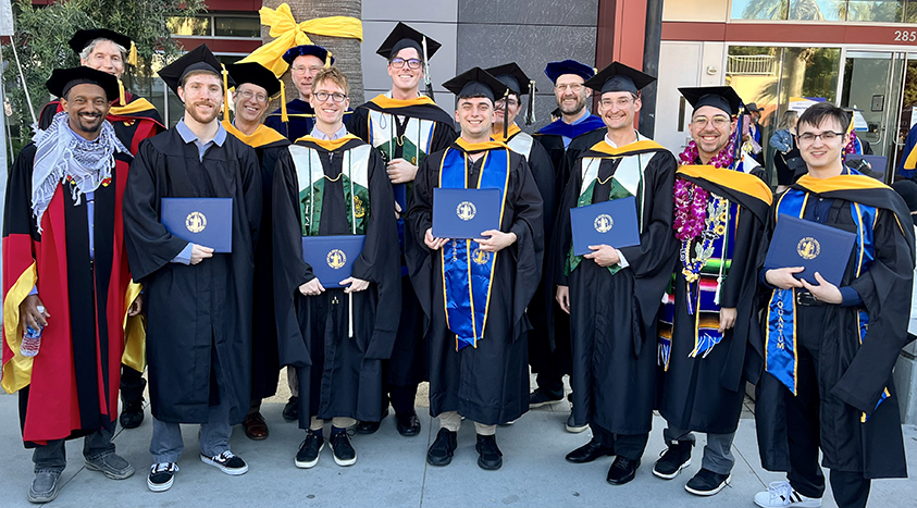 Group photo of graduating students and faculty members in regalia.